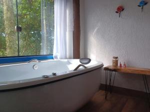 a bath tub in a bathroom with a window at Sopro da Serra Chalé Papagaio in Gonçalves +23 photos