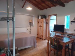 a bedroom with a bed and a desk and a table at Sopro da Serra Chalé Papagaio in Gonçalves
