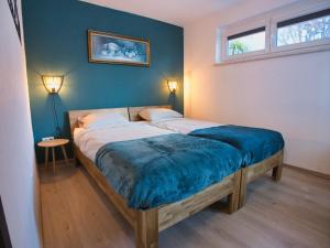 a bedroom with a bed with a blue blanket on it at Jagerheim Apartments Flattach in Flattach