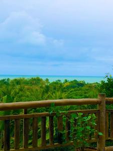 a wooden fence with the ocean in the background at Eliza, Bangalô vista mar em Trancoso in Trancoso