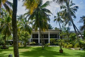 a building with palm trees in front of it at BREATHE Collections Habaraduwa in Habaraduwa