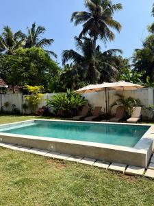 een zwembad met ligstoelen en een parasol bij Villa Carla Mirissa in Mirissa