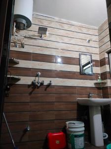 een badkamer met een houten wand met een wastafel en een spiegel bij Shiva Homestay in Rishīkesh