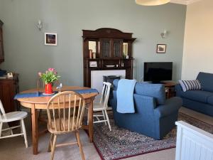 een woonkamer met een tafel en een blauwe bank bij The Store, harbour holiday cottage in Port Seton