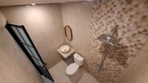 a bathroom with a toilet and a sink and a mirror at Kalih Rooms in Ubud