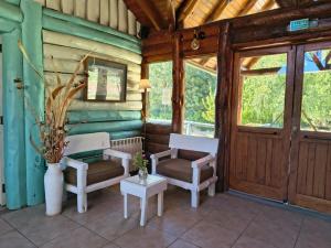 eine Veranda eines Hauses mit zwei Stühlen und einem Tisch in der Unterkunft El Refugio in Aluminé