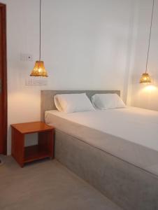a bed with two pillows and a table in a room at Emerald retreat in Ahangama