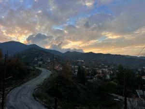 a winding road with a sunset in the mountains at ARTEMIS HOUSe in Kakopetria