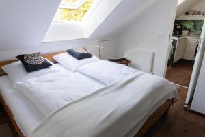 a bedroom with a bed with white sheets and a window at Casa La Vie Ferienwohnungen in Altenstadt