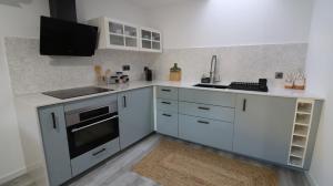 a kitchen with white cabinets and a sink and a stove at O Cantinho D'Alice in Sabugal