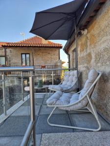 three lounge chairs and an umbrella on a balcony at O Cantinho D'Alice in Sabugal