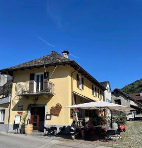 a yellow building with a table and an umbrella at Locanda Poncini in Maggia
