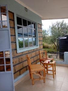 a patio with two chairs and a table and a window at Longonot View Camp and Accommodation, Naivasha in Naivasha