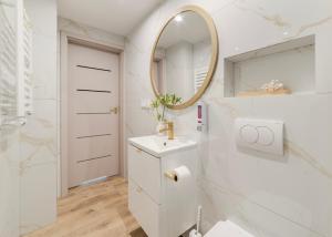 ein weißes Badezimmer mit Waschbecken und Spiegel in der Unterkunft Apartamenty Mieszka I in Łódź + 53 Fotos