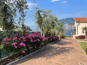a walkway with flowers and a view of the water at Appartamenti Villa Eden in Malcesine