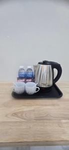 a tea kettle and two cups and bottles of water at SAMBATH SAKSETH Guesthouse in Phumĭ Nésat