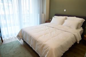 un grande letto bianco in una stanza con una finestra di ANESIS Luxury Apartments a Komotini