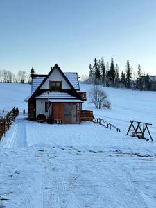 een hut in een met sneeuw bedekt veld met een hek bij WierchoHouse - domek z jacuzzi in Groń