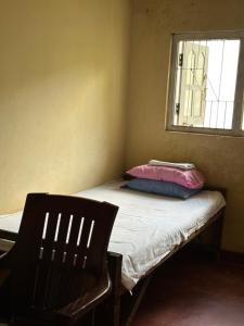 Piccola camera con letto, sedia e finestra. di Solo escape a Anuradhapura