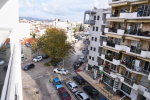 una strada cittadina con auto parcheggiate davanti agli edifici di ANESIS Luxury Apartments a Komotini