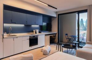 a kitchen with white cabinets and a living room at Aweso Limassol in Limassol