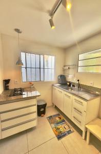 a kitchen with white cabinets and a sink at Cozy House in Pipa