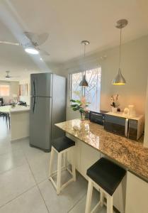 a kitchen with a refrigerator and two bar stools at Cozy House in Pipa +30 photos