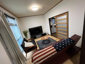 ein Wohnzimmer mit Sofa und Fernseher in der Unterkunft Entire house for rent in Beppu with a dog run in Beppu