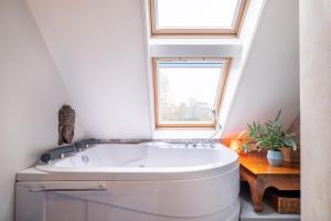 een badkamer met een wit bad en een raam bij LOFT Groepsaccommodatie in Boxum