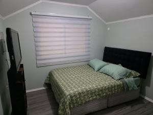a bedroom with a bed with a window and a television at Villa Parque Cordillera 1 in Chillán