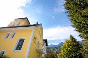 een geel gebouw met bergen op de achtergrond bij Parkvilla Appartements in Bad Hofgastein