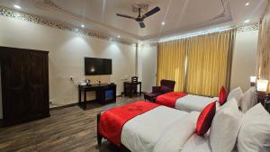 a hotel room with two beds and a television at Hotel Ranavilas Palace in Jaipur