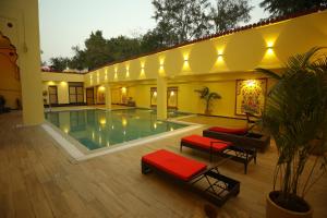 a large swimming pool in a building with red cushioned chairs at Hotel Ranavilas Palace in Jaipur