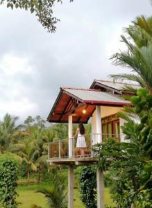 een vrouw op een balkon van een huis bij Forest & Fields Sinharaja in Deniyaya