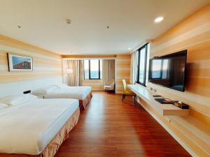 a hotel room with two beds and a flat screen tv at Wemeet Hotel in Pingtung City