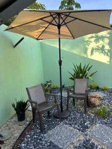 a patio with two chairs and an umbrella at Hibiscus Bliss Getaway in San Juan