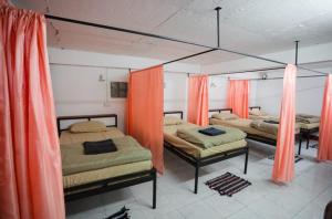 drie bedden in een kamer met oranje gordijnen bij Orlardee hostel in Thakhek
