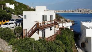 a white house on a hill with the ocean at Casa Santorini RJ in Arraial do Cabo