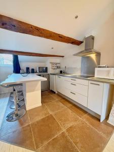 a large kitchen with white cabinets and a counter at Coeur Rochelais, Atypique, centre, 5 min du port in La Rochelle