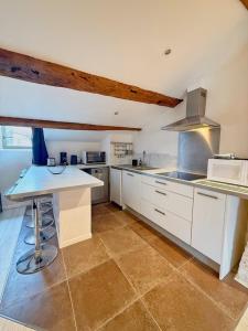 a large kitchen with white cabinets and a counter at Coeur Rochelais, Atypique, centre, 5 min du port in La Rochelle