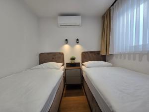 two beds in a hospital room with a window at Osijek Luxury Center - Self Check-in, 2 Parking Spaces, Balcony, Elevator in Osijek