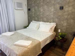 a bedroom with a bed with white sheets and pillows at Pousada Verde Serrath - Muriqui in Vila Muriqui