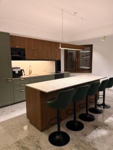 a kitchen with a large island with green bar stools at Willa Marie in Krynica Zdrój