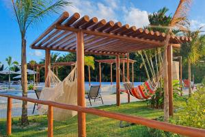 eine Gruppe von Hängematten unter einer Pergola neben einem Pool in der Unterkunft Refúgio com lazer completo em Pium RN in Parnamirim
