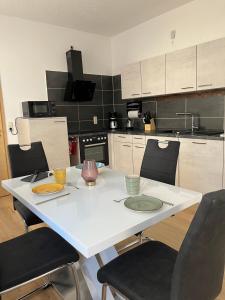 una cucina con tavolo bianco con sedie e una cucina di Ferienwohnung Lengenfeld a Lengenfeld