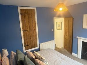 a bedroom with a bed and a blue wall at 2 Bed Terrace Cottage with Cathedral Views in Salisbury