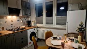 een keuken met een tafel en een witte koelkast bij Apartament Granatowy Chill in Łódź