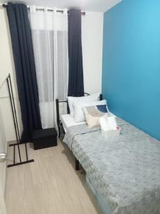 une chambre avec un lit et un mur bleu dans l'établissement AL KHOURY Staycation, à Tanza