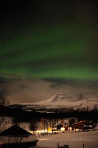 een noorderlicht in de lucht boven een besneeuwde berg bij Room in Cozy Cottage 