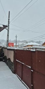 una recinzione coperta di neve accanto ad alcune linee elettriche di Pensiunea Ileana a Novaci-Străini